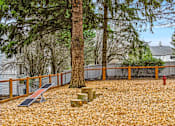 Thumbnail 19 of 26 - A playground with a slide, a tree, and a red fire hydrant.