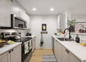 Thumbnail 5 of 24 - a kitchen with white cabinets and black appliances and a sink