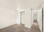 Thumbnail 14 of 26 - A long hallway with carpeted floors and white walls.