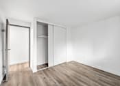 Thumbnail 11 of 13 - A room with a white wall and a wooden floor with a closet.
