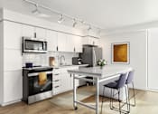 Thumbnail 6 of 26 - A modern kitchen with a white color scheme and stainless steel appliances.