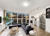 Thumbnail 2 of 26 - A modern kitchen with a large window and a black couch.