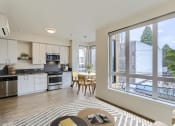 Thumbnail 17 of 33 - a living room with a large window and a kitchen with a table and chairs