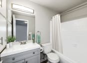 Thumbnail 7 of 15 - a bathroom with a white sink and toilet next to a white bathtub with a shower curtain