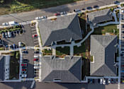 Thumbnail 20 of 34 - A parking lot with cars and a building with a grey roof.