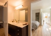 Thumbnail 7 of 27 - a bathroom with a sink next to a mirror and a bedroom in the background