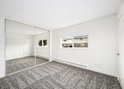 Thumbnail 44 of 49 - A large empty room with a grey carpet and a mirror on the wall.