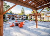 Thumbnail 6 of 49 - A wooden pergola over a patio with orange chairs and a table.