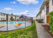 Thumbnail 1 of 15 - a fenced in swimming pool with orange lounge chairs and a building in the background