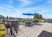 Thumbnail 25 of 48 - the rooftop patio of a building with tables and chairs and an umbrella