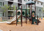 Thumbnail 16 of 24 - a playground with a slide in front of an apartment building