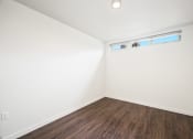 Thumbnail 35 of 48 - a bedroom with white walls and wood flooring and a window