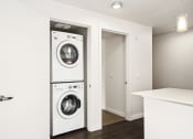 Thumbnail 44 of 48 - a white washer and dryer in a white laundry room with a door open