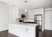 Thumbnail 41 of 48 - a white kitchen with a large island and stainless steel refrigerator