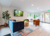 Thumbnail 10 of 24 - a living room with a blue couch and chairs and a tv on the wall