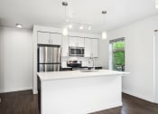 Thumbnail 43 of 48 - a white kitchen with a large island and a stainless steel refrigerator