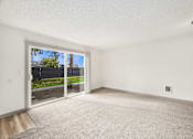 Thumbnail 40 of 49 - an empty living room with a sliding glass door to a yard