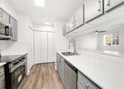 Thumbnail 5 of 25 - a white kitchen with stainless steel appliances and white counter tops