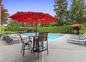 Thumbnail 24 of 29 - a swimming pool with a red umbrella and tables with chairs