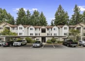 Thumbnail 25 of 29 - a parking lot in front of an apartment building with cars parked in front