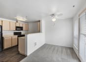 Thumbnail 8 of 29 - an empty living room with a kitchen and a ceiling fan