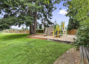 Thumbnail 18 of 29 - a playground in a backyard with trees and a picnic table