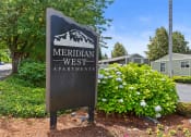 Thumbnail 10 of 22 - a sign for meridian west apartments in front of plants and trees