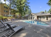 Thumbnail 31 of 35 - a swimming pool with chairs and a house in the background