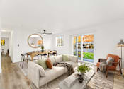 Thumbnail 2 of 25 - A living room with a white couch, a round mirror, and a ceiling fan.