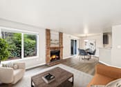Thumbnail 1 of 19 - A living room with a fireplace and a couch.