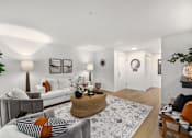 Thumbnail 11 of 24 - A living room with a grey couch, a white sofa, a woven basket on the rug, and a potted plant.