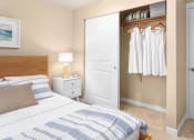 Thumbnail 15 of 26 - a bedroom with a bed and closet with a closet door and a closet with clothes