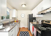 Thumbnail 16 of 30 - A kitchen with a black stove top oven and a clock on the wall.