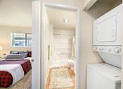 Thumbnail 21 of 30 - A small bedroom with a bed, a toilet, and a washing machine.