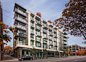 Thumbnail 2 of 38 - a large white building with green windows and a black car parked in front of it