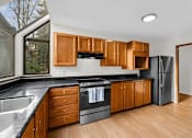 Thumbnail 4 of 41 - A kitchen with wooden cabinets and black countertops.