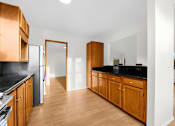 Thumbnail 6 of 41 - A kitchen with wooden cabinets and black countertops.