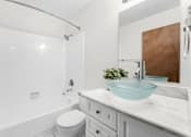 Thumbnail 29 of 41 - A white bathroom with a glass bowl sink and a white toilet.