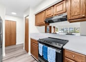 Thumbnail 5 of 41 - A kitchen with a black stove top oven and wooden cabinets.