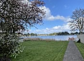 Thumbnail 35 of 41 - A park with a grassy area, a walking path, and a body of water.