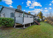 Thumbnail 8 of 41 - A house with a grey siding and a green lawn.
