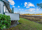 Thumbnail 37 of 41 - A house with a green bush in front and a field in the background.