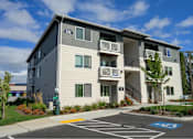 Thumbnail 11 of 34 - A modern apartment building with a parking lot in front.