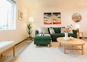 Thumbnail 15 of 34 - A living room with a green couch and a wooden bench.