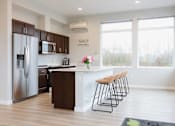 Thumbnail 22 of 34 - A kitchen with a refrigerator, microwave, and bar stools.