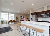 Thumbnail 23 of 34 - A kitchen with a bar area and chairs.
