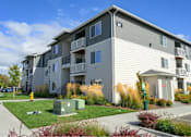 Thumbnail 32 of 34 - Apartment building with a green bush in front.