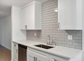 Thumbnail 14 of 29 - A kitchen with white cabinets and a grey tile backsplash.