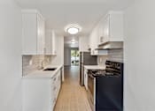 Thumbnail 6 of 29 - A modern kitchen with white cabinets and a black stove top oven.