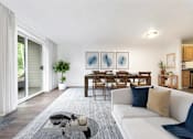 Thumbnail 7 of 29 - A modern living room with a white couch and a dining table.